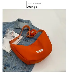 Détail d'un sac bandoulière orange en forme de lune avec un petit porte-monnaie rond