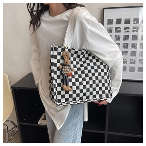 Detail of checkered canvas tote bag with a cute plush bunny charm worn on shoulder