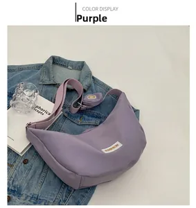 Détail du sac à bandoulière violet en forme de lune avec petit porte-monnaie sur jean
