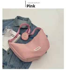 Détail du sac hobo demi-lune rose en nylon avec mini pochette ronde et étiquette