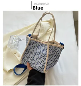 Detail of blue geometric tote bag with woven texture beside a cream blazer and strap