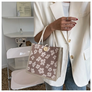 Detail of woven handheld bag with 3D floral pattern, cotton rope handle and wood button