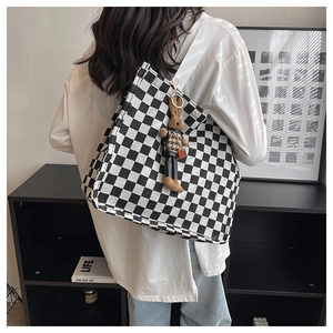 Black and white checkerboard canvas tote bag with a brown plush bunny charm detail