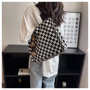 Detail of checkered canvas tote bag with a cute brown rabbit plush charm on strap