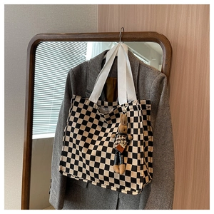 Detailed shot of checkerboard canvas tote with soft rabbit plush charm and wide handles