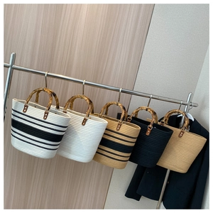 Detail of woven straw tote bags with bamboo handles in beige, black and white colors