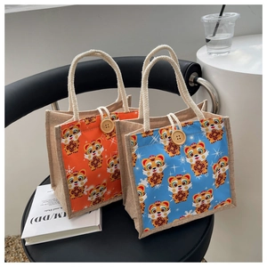 Detail of linen tote bags featuring cartoon tiger prints and rustic wooden buttons