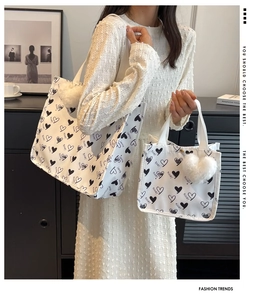 Detail of white canvas tote bag with black heart prints and plush heart keychain