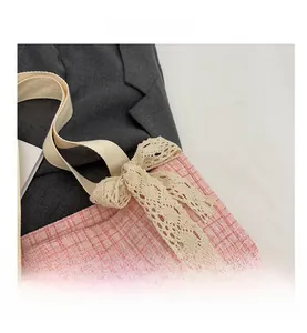 Detail shot of pink plaid tweed bag featuring cream lace bow and cotton woven strap