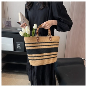 Detail of woven straw tote bag featuring striped pattern and vintage bamboo handles