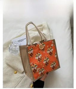 Detail of orange linen tote bag featuring a cute cartoon tiger print and wood button closure