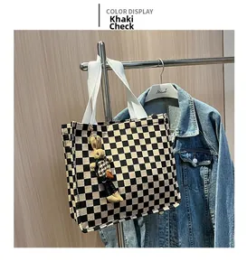 Detail of checkered canvas tote bag with shoulder strap and plush rabbit charm