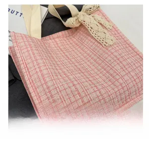 Detail of pink plaid canvas tote bag showing lace bow and tweed fabric texture