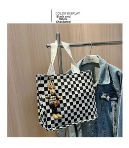 Detail of checkered canvas tote bag with bunny charm and white woven handles