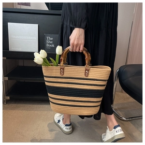 Straw tote bag detail with bamboo handles and chic black stripes on woven material