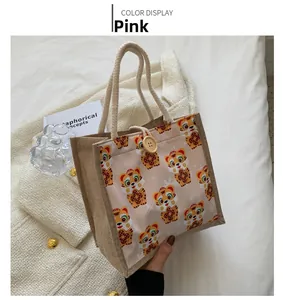 Detailed view of pink linen tote bag with cartoon tiger patterns and wooden button closure