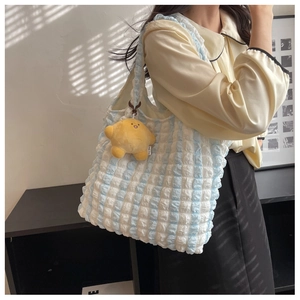 Detail of blue and white popcorn texture tote bag with yellow plush star pendant charm