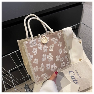 Close-up of linen tote bag featuring 3D floral accents and rustic rope handles