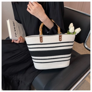 Detailed view of striped woven tote bag featuring natural bamboo handles and white tulips