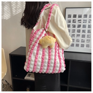 Detail of pink striped puff shoulder bag with yellow star plush charm in use
