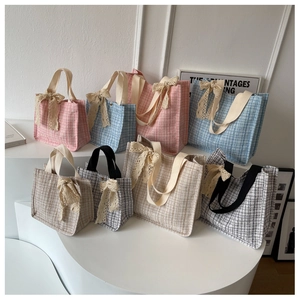 Detail of tweed tote bags in various colors featuring lace bow accents and soft handles