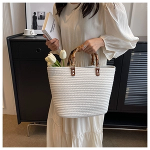 Detail of woven straw tote with bamboo handle and elegant white tulip flower inside