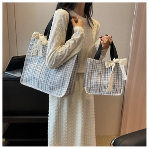 Detail view of large and small black tweed tote bags with white lace bow accents