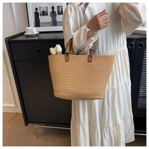 Detail of a beige woven tote bag with authentic bamboo handles and leather fasteners