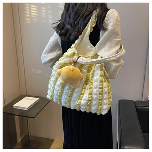 Detail of yellow striped pleated puffer bag with cute star plush keychain accessory