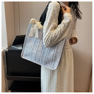 Detail of tweed tote bag with black and white plaid pattern and a cream lace bow