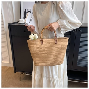 Detail of straw woven tote bag featuring bamboo handles and white tulip decoration