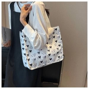 Detail of white canvas tote bag with black heart patterns and Nice text embroidery