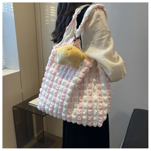 Detailed seersucker texture on pink and white tote bag with cute croissant plush charm