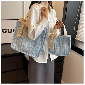 Detail of blue tweed tote bags set with cream lace bows and classic plaid texture