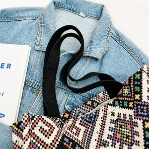 Dettaglio della borsa tote jacquard etnica con tracolla nera su giacca di jeans