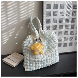 Close-up of blue checkered puffy tote bag featuring star pendant and bubble texture