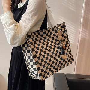 Fashionable checkerboard canvas tote bag with bunny charm shown on shoulder