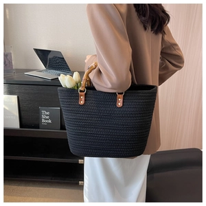 Detail of black woven tote bag featuring natural bamboo handles and textured cotton rope