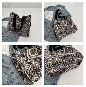 Detail of colorful geometric knit tote bag with thick black handles on casual denim background