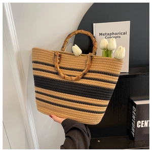 Detail of straw woven tote with black stripes and natural bamboo handle for beach style