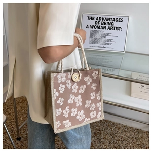 Detail of grey-pink woven tote bag with white floral embroidery and cotton rope handle