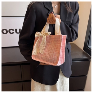Close-up of pink tweed tote bag with delicate white lace bow and sturdy woven handles