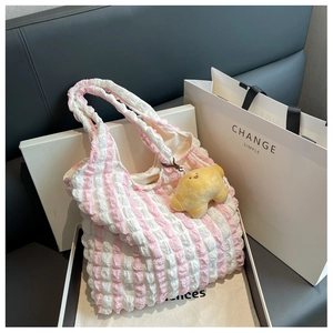 Detail of pink striped bubble textured tote bag with cute croissant plush charm