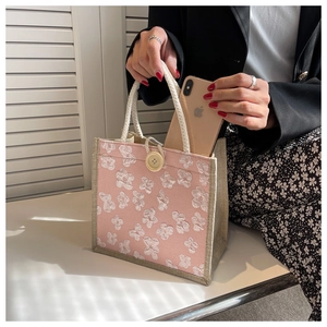 Detailed close-up of pink woven tote bag with 3D floral embroidery and round button closure