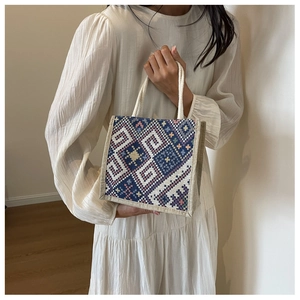 Nahaufnahme einer Canvas-Handtasche mit geometrischem Muster und weißen Baumwollgriffen