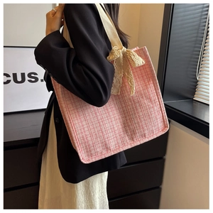 Detailed texture of pink tweed tote bag with delicate lace bow and wide shoulder strap