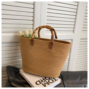 Detail of woven straw tote bag with textured bamboo handle and leather attachments