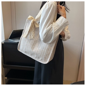 Close-up of woven tote bag featuring a cream lace bow and stylish checkered pattern