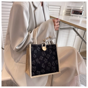 Detail of floral jacquard tote bag featuring wooden button and braided cord handles