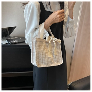 Detail of cream tweed mini tote bag featuring a delicate beige lace bow decoration